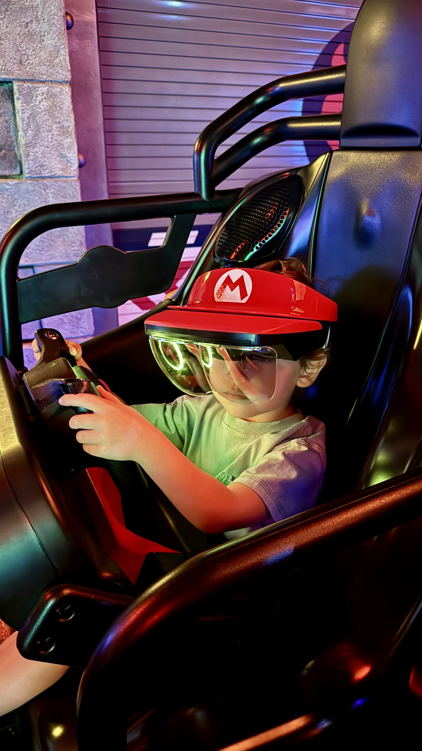 Sam no simulador Mario Kart Bowser's Challenge com capacete AR e chapéu do Mario no Super Nintendo World Epic Universe Orlando