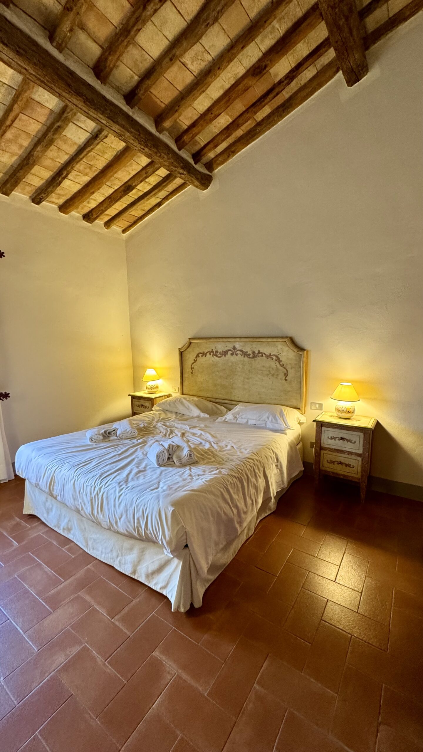 Quarto com cama king, vigas de madeira e piso de terracota na Riserva di Fizzano no Chianti