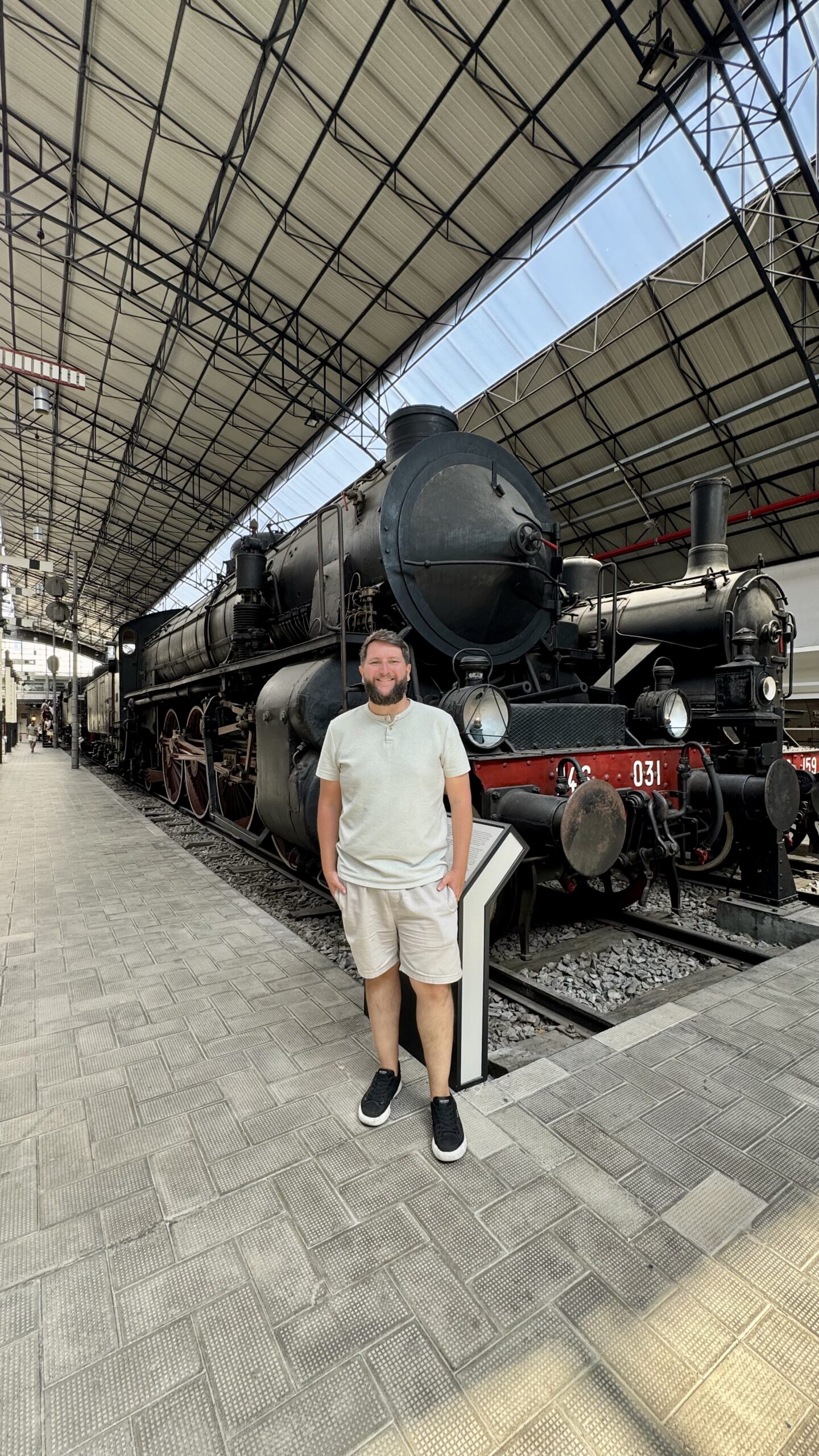 Homem em frente a uma locomotiva histórica no Museu Leonardo da Vinci em Milão